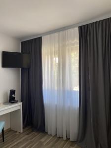 锡比乌Roomzzz Sibiu的客房设有带窗帘的窗户和书桌。