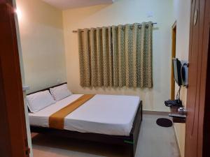 迈索尔Royal Suvarna Comforts的一间小卧室,配有一张床和电视