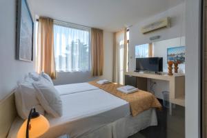 索佐波尔Hotel Odyssey Sozopol的一间卧室配有一张带书桌和电视的床。