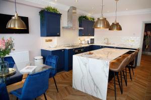 马伯斯Sea Watch Seafront Holiday House的一间设有蓝色橱柜的厨房和一个带蓝色椅子的厨房岛