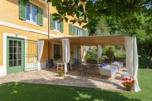 卡麦奥雷Villa Borgovecchio B&B的房屋前设有带天蓬和椅子的天井。