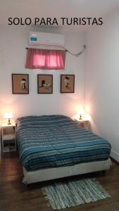 罗萨里奥Experiencia cultural rosarina的一间卧室配有一张带两盏灯的床,墙上有两张照片