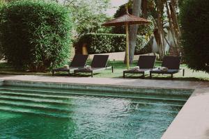 哈维亚Hotel Ritual de Terra & SPA的游泳池旁的2把躺椅和遮阳伞