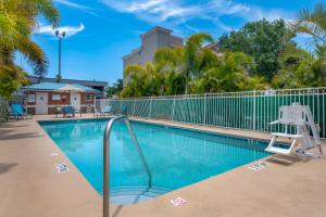 墨尔本墨尔本棕榈湾拉金塔旅馆及套房的一个带椅子的游泳池,靠近围栏