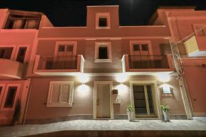 兰佩杜萨Domus B&B Le Nereidi的粉红色的建筑,晚上有灯