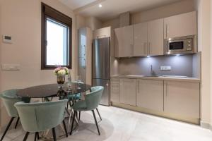 格拉纳达BiBo Suites Real Chancilleria的厨房配有桌椅和冰箱。