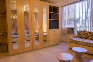 檀香山库西奥班盐酒店（带小厨房）的客厅设有大型木隔板和电视