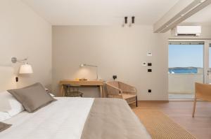 萨利MAIORA Luxury Island Suites的一间卧室配有一张床、一张书桌和一个窗户。