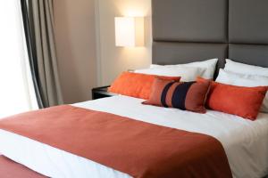 布宜诺斯艾利斯卡尔斯酒店的一间卧室配有一张带橙色枕头的大床