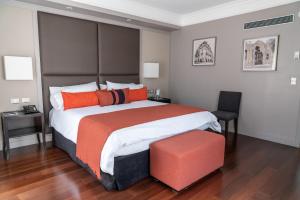 布宜诺斯艾利斯卡尔斯酒店的一间卧室配有一张带橙色枕头的大床