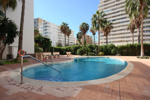 卡尔佩Apartamento Frentemar 2 - Costa CarpeDiem的棕榈树庭院内的游泳池,以及建筑