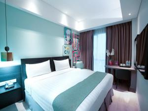 雅加达Brits Hotel Puri Indah的酒店客房设有一张大床和一张书桌。