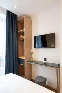 巴黎HOTEL AU COEUR DES ARTS ET METIERS的一间卧室配有一张床,墙上配有电视