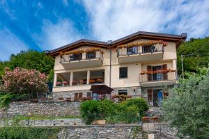 梅纳焦Foresteria Lago di Como的山上的一座房子,阳台上种着鲜花