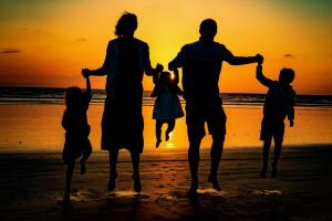 奥欣赛德G218 - Palms Away的日落时分在海滩上散步的家庭