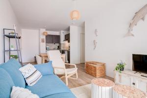 拉卡诺Ressourcez vous dans ce bel appartement a Lacanau的一间带蓝色沙发的客厅和一间厨房