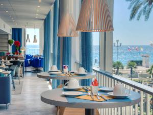 尼斯尼斯英国大道美居酒店的一间设有桌子并享有海景的餐厅