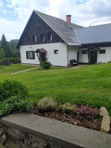 济泽罗河畔帕塞基U Tomíčků的一间白色的房子,有黑色的屋顶和院子