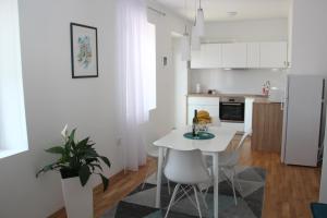 蒂瓦特Apartment Lana的白色的厨房配有白色的桌子和椅子