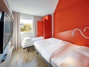 拜罗伊特ibis budget Bayreuth的橙色墙壁的客房内的两张床