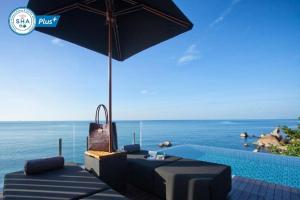 拉迈Silavadee Pool Spa Resort - SHA Extra Plus的一座带椅子和遮阳伞的游泳池,毗邻大海