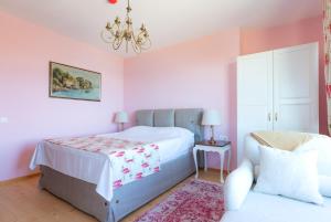 索佐波尔Luxury 3-bedroom villa in Sozopolis with sea view的卧室设有粉红色的墙壁、一张床和一个吊灯。