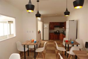 罗萨里奥Real Ros Hostel的厨房以及带桌子和白色椅子的用餐室