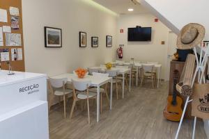皮尼昂Hostel Douro Backpackers的餐厅设有白色的桌椅和电视。