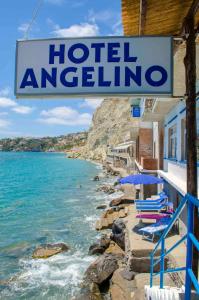 伊斯基亚Hotel Angelino的海滩上酒店标志,上面有椅子和遮阳伞
