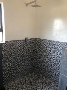 哈博罗内Villa 134 Modipane的浴室设有黑色和白色的瓷砖墙