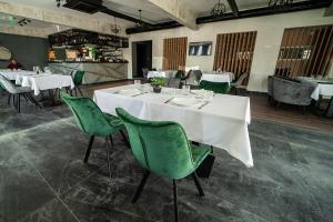 贝尔格莱德Hotel GardeNN的用餐室配有白色的桌子和绿色的椅子