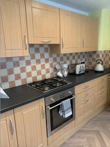 福尔柯克Grangemouth Apartments的厨房配有木制橱柜和炉灶烤箱。