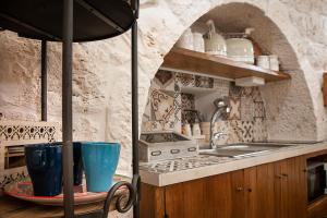 洛科罗通多LiberaMente - Trulli & Quiete的厨房配有水槽和带杯子的桌子