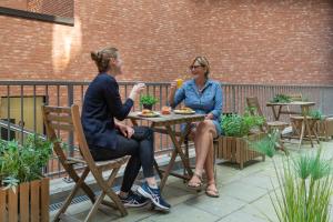 奥斯陆奥斯陆智能酒店的两个坐在餐桌上吃食物的女人