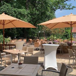 希勒Hotel Le Filou的一个带桌椅和遮阳伞的庭院。
