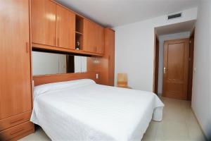 卡拉费尔Apartamento Plaça Jardí的卧室配有白色的床和木制橱柜。