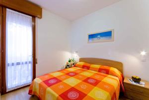 比比翁Apartment in Bibione 24409的一间卧室设有一张色彩缤纷的床和一个大窗户