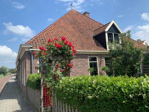 埃丹"De Walvisch", appartement in authentieke boerderij的一座房子,上面有红玫瑰围栏
