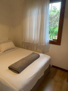 圣若昂-德雷Casa COMPLETA, 2 quartos, Estacionamento GRATUITO, WIFI 300MB, frigobar, microondas, fogão e jardim的一间卧室配有一张带窗户和枕头的床