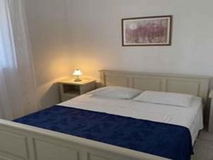 尼亚卢卡Holiday home in Vela Luka 6375的一间卧室配有一张床和一张带台灯的桌子