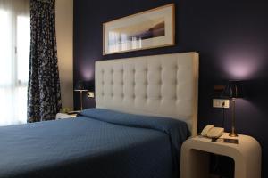 里瓦德奥博萨酒店的一间卧室配有一张床,桌子上配有一部电话