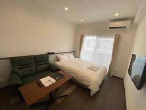 宫古岛HOTEL GranLeaf Miyakojima的客房设有床、沙发和电视。