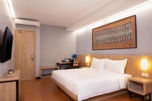 查亚普拉BATIQA Hotel Jayapura的卧室配有一张白色大床和电视。