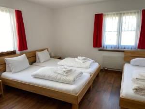 安德马特Berggasthaus Piz Calmot的配有窗户和红色窗帘的客房内的两张床
