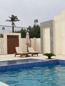 塞拉莱Hawana Salalah lagoon beach apartment的一个带2把躺椅和遮阳伞的游泳池