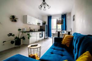 伊拉华Apartament WHITE的一间带蓝色沙发的客厅和一间厨房