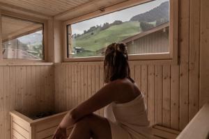 萨尔巴赫FRAU GANS - pure mountain apartments的坐在桑拿浴室里,看着窗外的女人