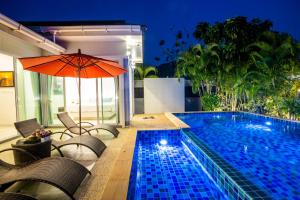 奥南海滩3 Bedroom Exclusive Private Pool Villa Smooth as Silk的一个带椅子和橙色遮阳伞的游泳池