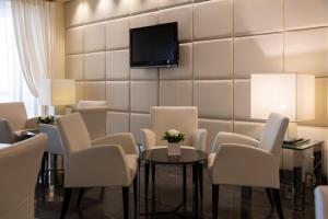 加尔达湖滨安蒂科博尔戈酒店的一间设有白色椅子和墙上电视的等候室