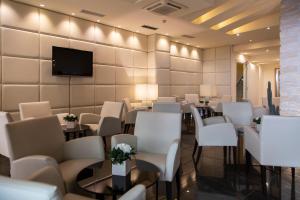 加尔达湖滨安蒂科博尔戈酒店的一间设有白色椅子和桌子以及电视的房间